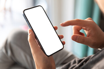 Man using smartphone blank screen frameless modern design while lying on the sofa in home interior