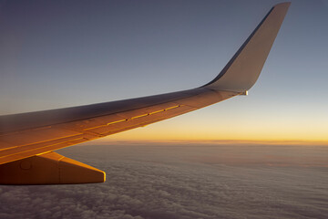Lot samolotu przy wschodzie słońca, widok na skrzydło samolotu.  - obrazy, fototapety, plakaty