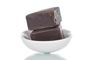 Two sweet chocolate candies on a white ceramic saucer, close-up, isolated on white.