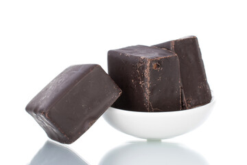 Three sweet chocolate candies on a white ceramic saucer, close-up, isolated on white.