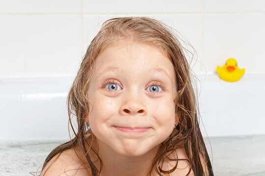 Cute, beautiful, cheerful little girl with long hair in the bathroom. Children's emotions with soap bubbles. Children's hygiene. Water games. Hygiene of the child. Health