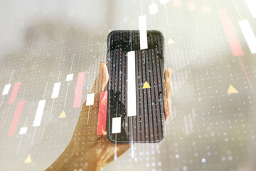 Multi exposure of abstract creative financial graph with world map and hand with phone on background, forex and investment concept