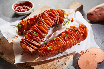 Deep-fried spiral sweet potatoes served with tomato sauce and fresh green herbs on a wooden board