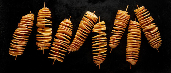 Golden crispy tornado potatoes as traditional Korean street food isolated on black background
