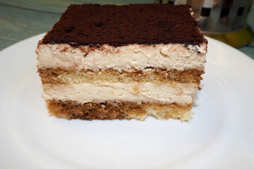 a piece of tiramisu cake with mascarpone cream is on a white plate. side view