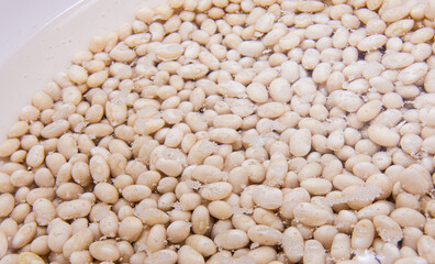 White beans soaked in water. Preparation of legumes before cooking soup.