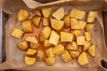 Chopped fresh potatoes into small pieces and drizzled with oil and spices to prepare American potatoes by baking in the oven