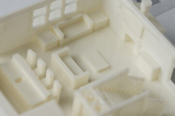 Close-up of 3D model of the house first floor with furniture printed on a 3D printer with white filament by FDM technology.