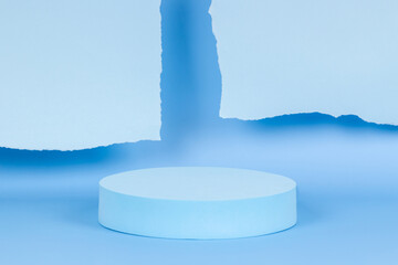 Abstract monochrome composition with empty round podium platform for product presentation and torn paper edges on light blue background. Front view