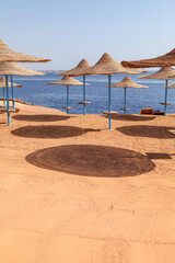 Beach straw umbrellas on the background of the blue sea. Beach Vacation