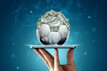 Dollars are inside the soccer ball, the ball is filled with money in a smartphone. Sports betting,...