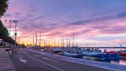 Fototapeta na wymiar View of Sunrise Over Fishing Boats With Colofull Clouds in the Sky