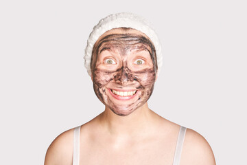 Young woman applying black face mask. Wow emotion. Charcoal facial product. Acne and pimple removing. Mud coal therapy. Fresh dermatology scrub. Copyspace. Cosmetology wellness procedure