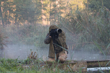Masked photographer in the forest, hidden and well hidden like a chameleon, nature photography