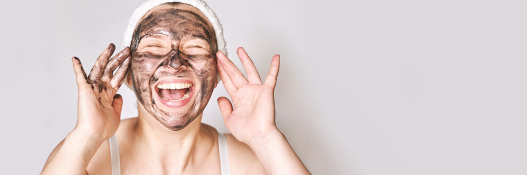 Young woman applying black face mask. Charcoal facial product. Acne and pimple removing. Mud coal therapy. Fresh dermatology scrub. Copyspace. Place for ads text. Cosmetology wellness procedure