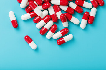 A handful of Red and white pill capsules on a blue background. Free space Top view