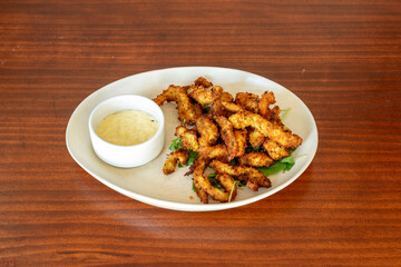 Chicken strips battered with flour seasoned with garlic and parsley and with mayonnaise sauce for dipping