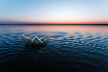 A paper ship made from banknotes, made from dollars, floats in the water against the backdrop of a...