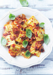 Ravioli with mushrooms and fresh basil. Bright wooden background. Top view. 