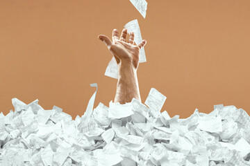 A man's hand sticks out of a mountain of checks and bills. A man is drowning in debt, credit,...