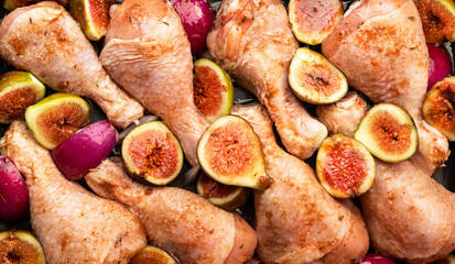 Raw chicken legs, drumsticks with sweet figs and red onions in balsamic marinade prepared for baking on baking sheet, close uo, top view