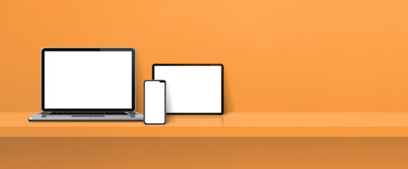 Laptop, mobile phone and digital tablet pc on orange wall shelf. Banner background