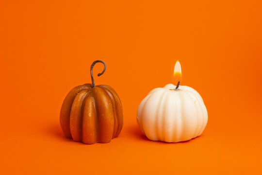 miniature pumpkin candles on orange background close up. halloween, thanksgiving, harvest festival concept