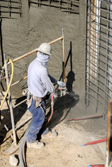 Construction worker operating a shotcrete pressure hose and nozzle