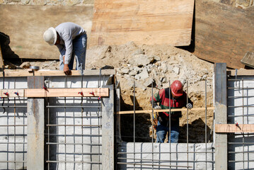Construction workers installing wooden ground boards on a retaining wall