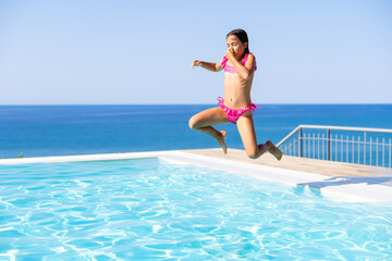 Closeup portrait of cute little arabic girl swimming in the pool, happy child having fun in water, beach resort, summer vacation and holidays concept
