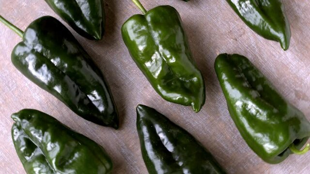 Green raw poblano peppers top view on table. Home-grown pepper vegetables rotating top view.