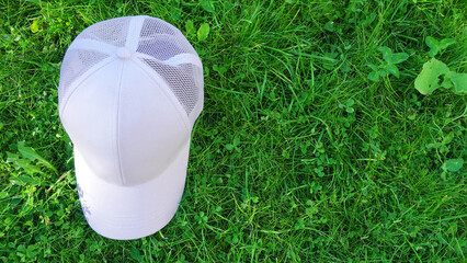 White baseball cap mock up on bench. Photo of blank hat for change design. Element for branding on green grass