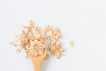 Top view of dry rolled oatmeal in wooden spoon isolated on white background.
