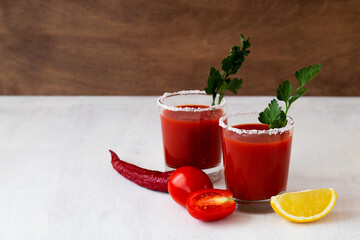 Tomato juice with salt. Bloody Mary cocktail with ingredients. Alcoholic drink with vodka and tomato juice in a glass isolated on a white background. vampiro cocktail with pepper on table. copy space.
