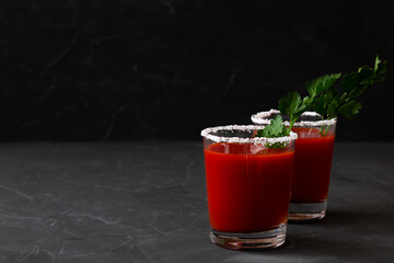 Two Glasses with Tomato juice with pepper, spices, salt and ice in glass with copy space. Bloody Mary cocktail. Alcoholic drink with vodka, vampiro cocktail on the black background.