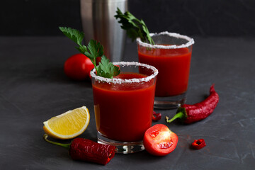 Fresh Tomato juice with pepper, spices, salt and yellow lemon in glass with copy space. Bloody Mary cocktail. Alcoholic drink with vodka, vampiro cocktail and ingredients on the black background.