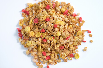 Granola with nuts and pieces of dry strawberries. Delicious and healthy breakfasts. Oat flakes with cornflakes and nuts on a white background top view. Dry muesli with fruits.