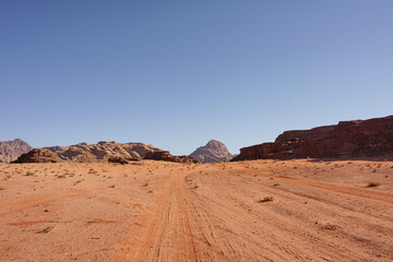 Fototapeta na wymiar the road in the Wadi Rum desert is directed to the red relief mountains, the blue cloudless sky, the nature of Jordan