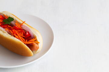 homemade hot dog on the white plate. close-up Hot dog with pickles, fried onions, sauce and ketchup on a white background in a restaurant. Fast food concept with copy space.