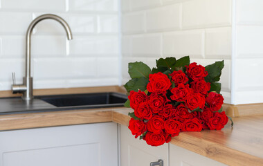 Valentine's Day and kitchen interior. For my Valentine. Close-up photo of a bouquet of red roses which lie on a kitchen table.