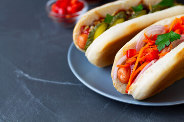 hot dog with ketchup.Close-up Different tasty homemade hot dogs with tomato, cucumber, onion, salad, carrots, spices and mustard, ketchup on a dark table with copy space. Fast food concept