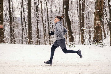 Fast runner running in forest at snowy winter day. Healthy lifestyle, winter fitness, cardio