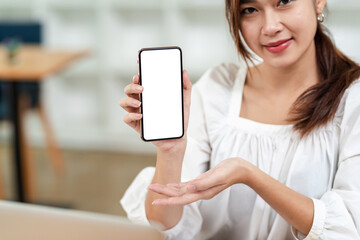 Image of an Asian businesswoman holding a smartphone blank white screen on a looking at the camera.