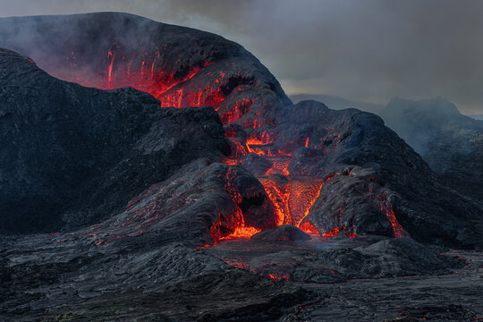 Side view of the crater opening from Fagradalsfjall volcano. Crater shortly after the lava flow on Iceland in the GeoPark. Clouds and steam in the sky. Daytime vulcanic eruption on Reykjanes peninsula