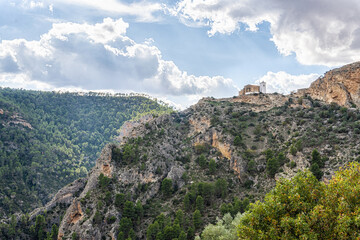 Mountainous landscape with the sanctuary of El Cristo de la Vida on top of the mountain, with the blue sky with sun and clouds. In Villa de Ves, Albacete (Spain). 