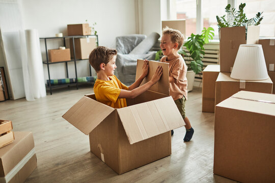 Portrait of two boys playing in cardboard boxes while family moving to new house, copy space