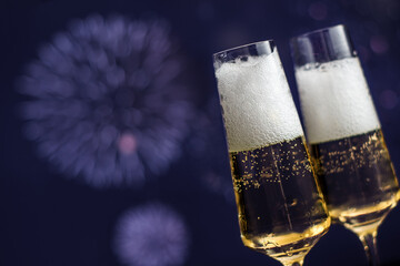 Pair of glasses of sparkling wine against background of fireworks with copy space