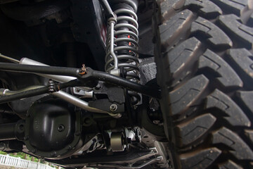 Off-road car chassis with a detailed view of the coil spring at the front wheel. - obrazy, fototapety, plakaty