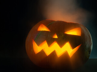 Glowing pumpkin jack-o-lantern on a dark background.