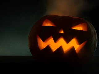 Glowing pumpkin jack-o-lantern on a dark background.